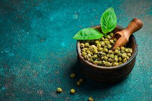 Green pepper peas in a wooden bowl. Spices and condiments. Top view. On an old background. photo