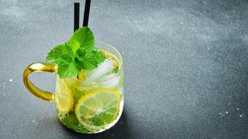 Refreshing summer alcoholic cocktail mojito with ice, lemon and mint. On a dark stone table. photo