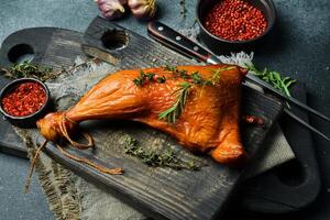 Smoked chicken leg with spices and rosemary. On a black stone background. photo