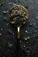 Black caviar in a spoon. Macro photo of caviar. On a concrete background. Top view.