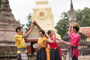 Young Thai people dress in traditional Thai costumes and play in the water during Songkran. photo