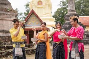 Young Thai people dress in traditional Thai costumes and play in the water during Songkran. photo