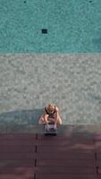 Caucasian woman working remotely on the computer while sitting in swimming pool video