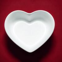 ai generado un blanco en forma de corazon plato se sienta vacío en un superficie. ai generativo foto