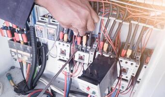 el proceso de reparando eléctrico componentes en el máquina controlar panel, un electricista usos un destornillador a reparar el eléctrico controlar circuito componentes.apriete el terminales cable fuerza. foto