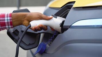 A man's hand preparing to charge an electric car. Black man charging cargo electric car video