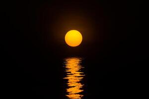 Big orange sun is reflection on the dark water photo