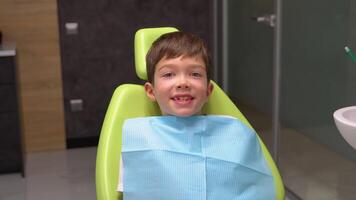 pequeño chico sentado en del dentista silla y mirando a cámara video