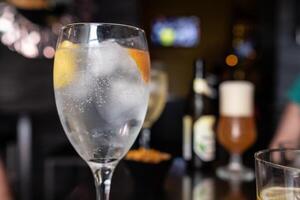 vodka glass with lemon and orange slice in cocktail bar photo