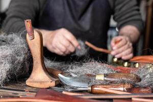 Leather craftsman tools in the foreground with man working behind photo