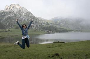 woman jumping for joy in front of a lake in a mountainous landscape, in lakes of covadonga photo