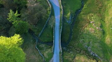 antenne visie van een kronkelend rivier- snijdend door levendig groen velden met een klein brug kruispunt over. video