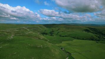 Aerial view of rolling green hills under a blue sky with fluffy clouds. video