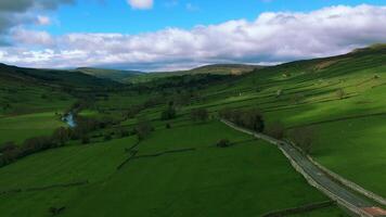 Breathtaking aerial view of lush green valleys with a winding road under a cloudy sky. video