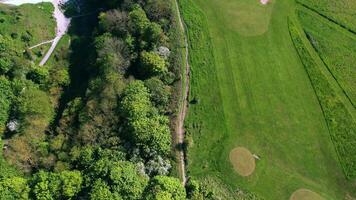 Aerial view of a lush green golf course with sand bunkers near a coastline, showcasing natural beauty and recreational theme. video