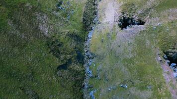 Aerial view of a narrow stream flowing through a lush green valley. video