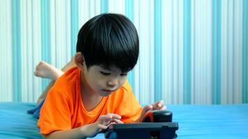 A little Asian boy is filming an online video outdoors while going to the beach.