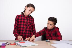 smiling child pointing the result of a problem to a girl in the notebook photo