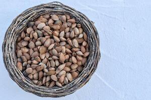 basket of almonds with peel seen from above on light background photo