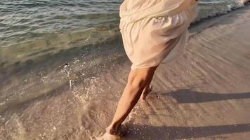 Close up of a persons barefoot walking along a sandy beach, with waves gently lapping over their foot, depicting a serene summer day or a tranquil vacation concept video