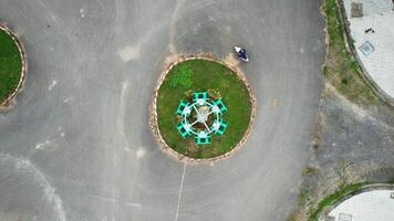 antenne visie van een persoon rijden een motor in de buurt een stedelijk rotonde, presentatie van elke dag stad leven van bovenstaand en de concept van leven cirkel video