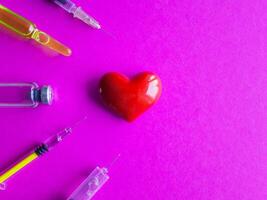 volumetric heart with syringes on a pink background. The concept of supporting patients with heart disease photo