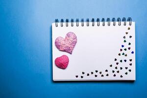 Simple blue background with a small purple red heart yn notebook. Place for text photo