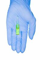 Green capsules ampoule held by hand in medical glove, isolated on white background. Chemotherapy photo