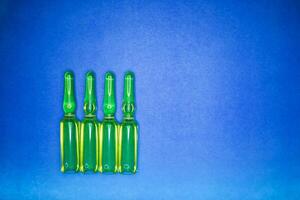 Medical ampules for injection isolated on blue background. Ampoules with botox, hyaluronic, collagen or vitamins photo