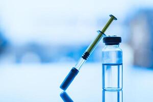 Vials of medication and syringe on a blue glass table with window background photo