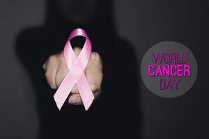 Pink ribbon for breast cancer awareness, symbolic bow color raising awareness on people living with women's breast tumor illness. With text WORLD CANCER DAY photo