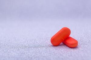 Two red capsules of medical pills isolated background photo