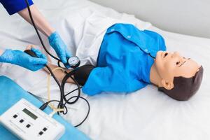 médico estudiante medidas sangre presión en un ficticio. formación en médico práctica en el formación hospital foto