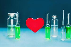 Concept of a healthy heart. Red volumetric heart on the background of ampoules with medicines photo