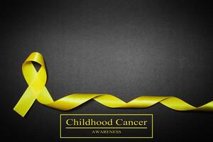 childhood cancer awareness day. Yellow ribbon on black background. photo