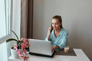 A young beautiful girl at home is working on a laptop, discussing business ideas with a partner photo