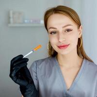 Portrait of a cosmetologist in the office with a syringe. Injection procedure for lip augmentation. Advertising concept for facial care, youth and beauty. photo