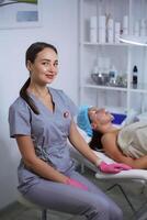 Happy female cosmetologist. Portrait pretty woman wearing pink gloves and uniform. Beauty, cosmetology concept. photo