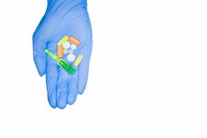 Embezzlement of hospital drugs. Green capsules, pills, ampoule held by hand in medical glove, isolated on white background. photo