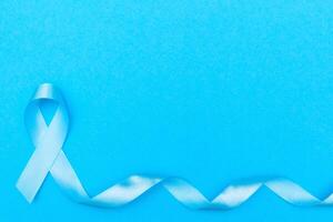 blue cancer awareness ribbon with trail on blue background. concept of health and medicine photo