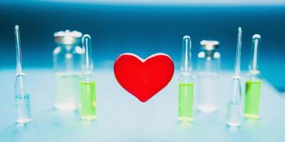 Concept of a healthy heart. Red volumetric heart on the background of ampoules with medicines photo