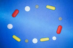 frame from multi colored pills and capsules on blue background. photo