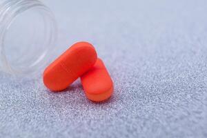 Two red capsules of medical pills isolated background photo