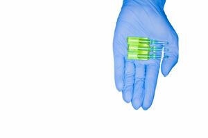 Green capsules ampoule held by hand in medical glove, isolated on white background. Chemotherapy photo