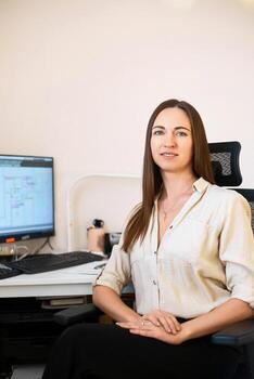 retrato de un remoto obrero. un hermosa sonriente morena niña se sienta a un mesa en frente de un computadora y trabajos con un disposición. confidente joven dama persona de libre dedicación trabajando desde hogar. foto