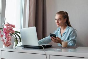 un joven mujer utilizando un ordenador portátil comunica terminado el Internet con un cliente desde el vivo habitación. acogedor lugar de trabajo, remoto trabajar, e-learning concepto foto