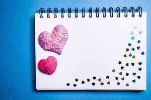 Simple blue background with a small purple red heart yn notebook. Place for text photo