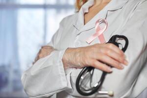 Pink cancer awareness ribbon on doctor's coat. World Cancer Day photo