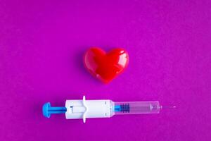 volumetric heart with syringes on a pink background. The concept of supporting patients with heart disease photo