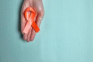 Red cancer awareness ribbon with trail on blue background. concept of health and medicine photo